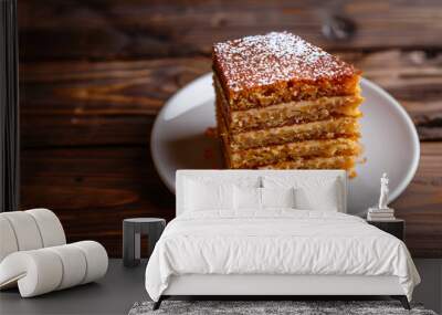 Tempting slice of honey layer cake rests on a plate atop a rustic wooden table Wall mural