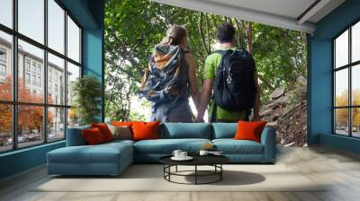 Leisure and tourism. Young couple hikers in tropical jungle holding their hands. Wall mural