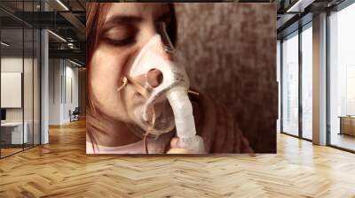 young woman is breathing in a nebulizer inhaler mask Wall mural