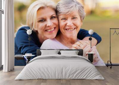 middle aged woman embracing disabled senior mother Wall mural