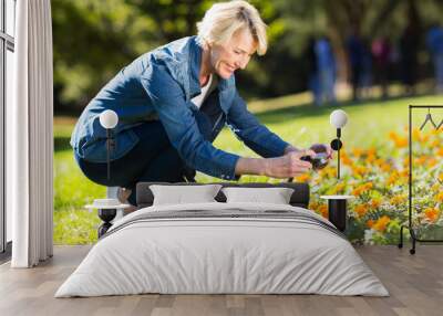 senior woman taking photographs of flowers Wall mural