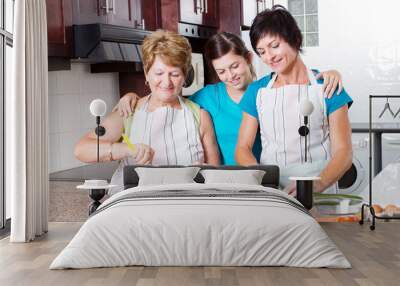 teen girl watching mother and grandmother cooking in kitchen Wall mural