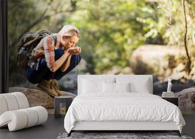 young hiker drinking stream water Wall mural