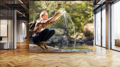 young hiker playing with stream water Wall mural