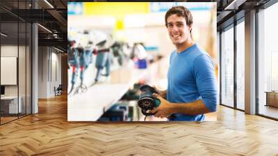 young man purchasing hand tool in hardware shop Wall mural