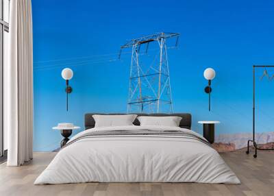 High voltage transmission tower with parallel lines on the top of the rocky hill in the blue sky Wall mural