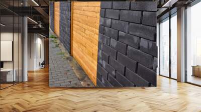 garden fencing where materials such as wood and rectangular concrete blocks are combined. between the walls are embedded pieces with planks. wet after rain Wall mural