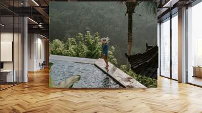 Young travelling girl swimming in the infinity pool in a luxurious home in Ubud, Bali, Indonesia.  Wall mural