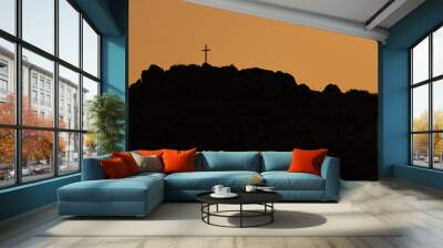 Catholic Cross on top of the rocky moutain at sunset. Wall mural