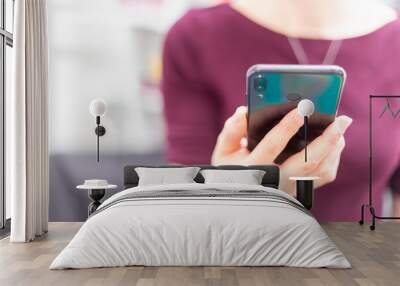 Close up view of a hand holding a cell phone. Woman working with phone, front view Wall mural