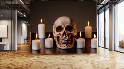 Skull with several candles of different sizes arranged around it Wall mural