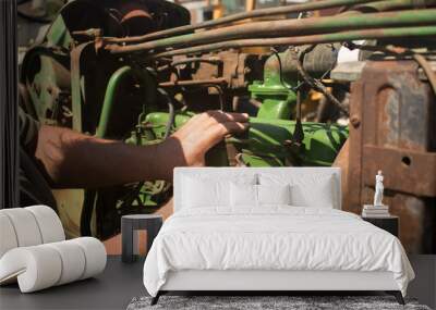 Close up of agricultural mechanic working on an antique green farm tractor outside in the sunshine Wall mural