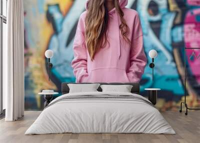 young woman with a pink hoodie and a wall with graffiti in the background. girl stays outdoor against graffiti wall, exuding urban chic.. Clothing mockup. Generative ai Wall mural