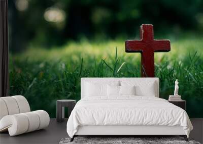 A red wooden cross stands tall in a lush green field of grass, symbolizing faith, hope, and the enduring nature of spirituality. The blurred background evokes a sense of peace and tranquility, enhanci Wall mural