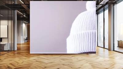 A white knit beanie with a fluffy pom pom, symbolizing warmth, comfort, winter fashion, style, and cozy vibes. Wall mural