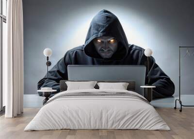 Hooded Figure with Glowing Eyes Using a Laptop - A man wearing a dark hooded jacket with glowing eyes uses a laptop, creating a mysterious and unsettling atmosphere. Wall mural