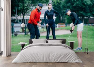 Golf putting lesson, two young female golfers practicing putting with golf instructor Wall mural