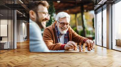 Senior man savors a game of chess with friends, a perfect blend of intellectual competition and camaraderie Wall mural