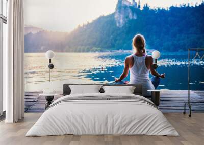 yoga lotus. young woman doing yoga by the lake, sitting in lotus. Wall mural