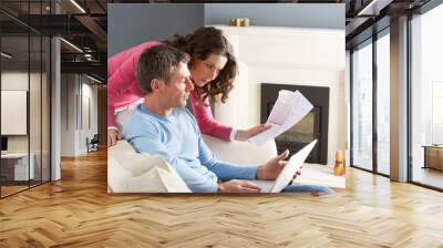 Couple Using Laptop And Discussing Household Bills Sitting On So Wall mural