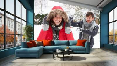 young couple having snowball fight Wall mural