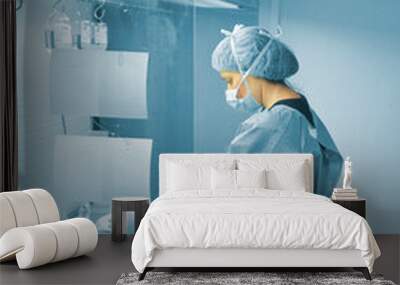 Female scientist working in the fume hood with a mask, cap, gloves and plastic pretreatment gown in the study against covid-19 Wall mural