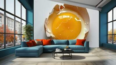 Cracked open egg shell containing a yellow yolk inside on a white background Wall mural