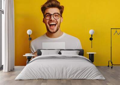 Happy young man holding a tcket gift, isolated on yellow background. Wall mural