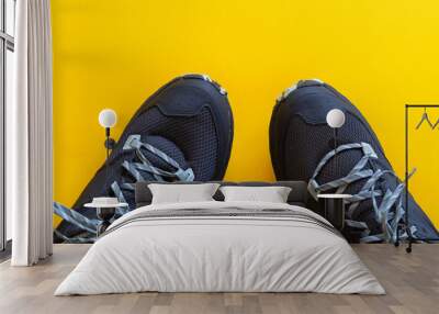 Partial view of a pair of black sports shoes on a yellow background Wall mural