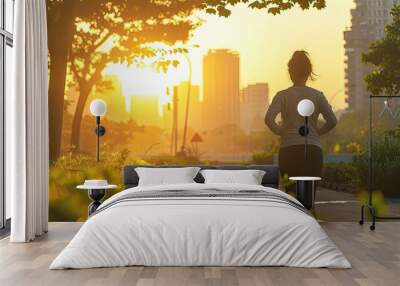 Silhouette of a girl running through the  park at sunset on a hot summer afternoon. Wall mural