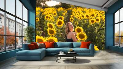 Chica joven guapa sonriendo y posando en un campo de girasoles Wall mural