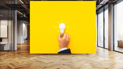 Businessman hand  holding lightbulb on a yellow background.  Inspiration ideas.
Motivation for success concept.

 Wall mural