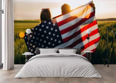 Image of young couple with the American flag in a wheat field at sunset. Independence Day, 4th of July.	 Wall mural