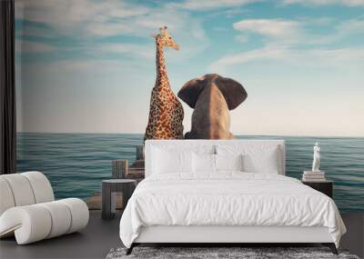 Giraffe sitting next to an elephant on wooden deck. Wall mural