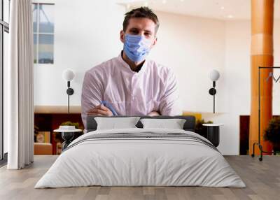 a young male doctor in uniform wearing the protective mask in hospital, medicine clinic Wall mural