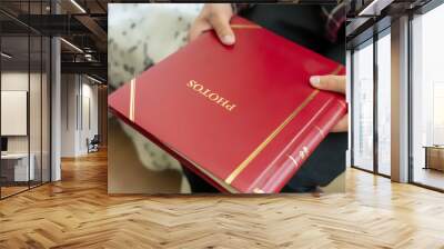 close up hands hold and open red family photo album sitting at home, past memory concept f Wall mural