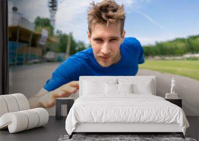 close up head portrait of a man running on a stadium track, fast speed motions Wall mural