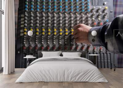 Close-Up of a Hand Adjusting the Controls on a Music Mixer Console in a Studio Wall mural