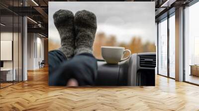 close up woman legs in warm wool socks in car and dring tea f Wall mural