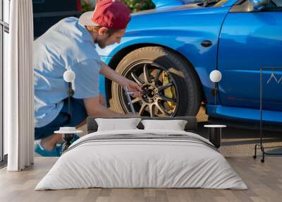 having some car issues on the roadside highway, man fix the auto wheel outdoors Wall mural