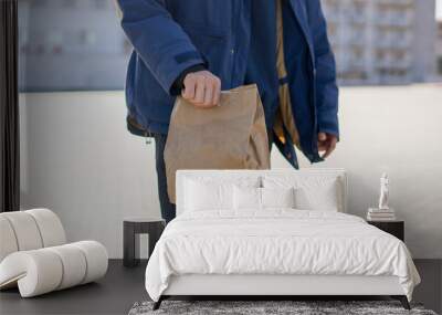 male courier carry the food delivery in the paper bag outdoors in the city Wall mural