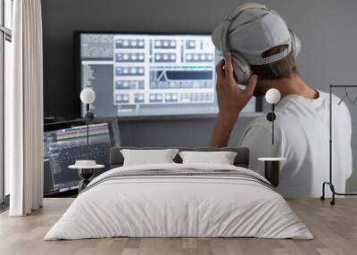 male producer in headphones doing music at home using computer Wall mural