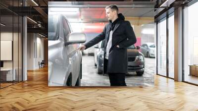 man opens his car in the underground parking zone f Wall mural