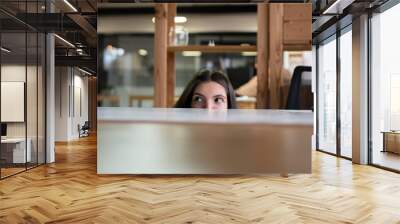 Office Worker Sneaking a Peek Above Laptop in a Modern Workspace During Daytime, hiding from boss Wall mural