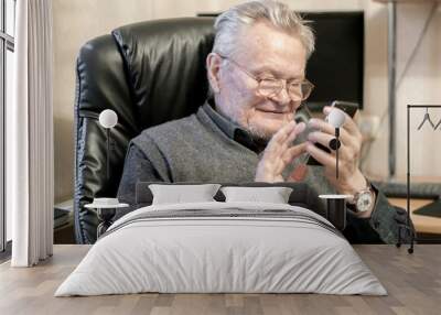 old senior man in glasses using mobile phone b Wall mural