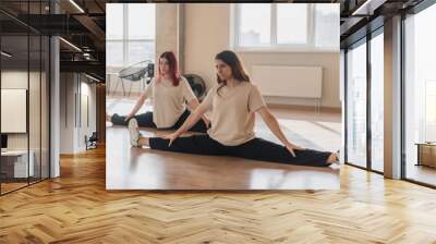 two girls on a group fitness training class in the gym doing stretching workout Wall mural