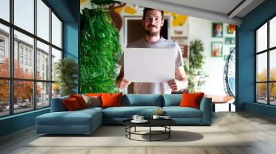 young man holding a white frame with copy space for text Wall mural