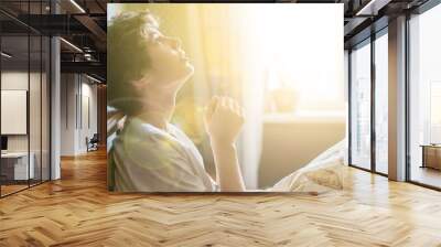 young man is praying in bed at home against the window b Wall mural