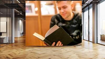 young man sitting at home library and read a book, chill and relax f Wall mural