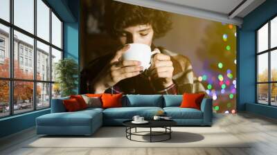 young sick teenager drinking hot tea cup under the blanket, struggle with illness at home in the night f Wall mural